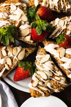 a white plate topped with slices of cake covered in frosting and sliced strawberries