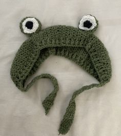 a crocheted hat with two eyes and a tie around the head is laying on a white sheet