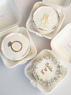 four white trays with wedding cakes and rings on them, one for the bride to be