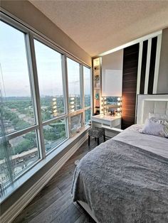 a bedroom with large windows and a view of the city from it's bed