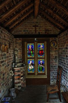 a room with two stained glass windows and a wooden bench in front of the door