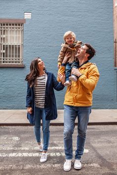 a man and woman walking down the street with a child on their shoulders, holding hands