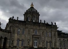 an old building with many windows and statues on the top, under a cloudy sky