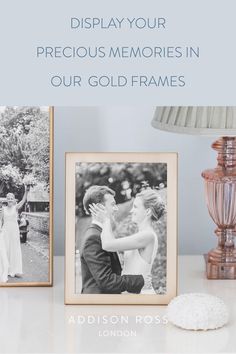 two framed photos next to a lamp on a table with the words display your precious memories in our gold frames