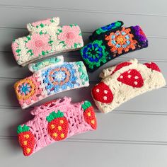 four crocheted hair clips with flowers and fruits on them, all in different colors