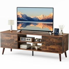 a flat screen tv sitting on top of a wooden entertainment center next to a lamp