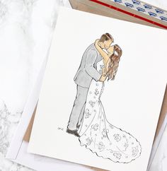 a wedding card with a drawing of a bride and groom hugging each other on top of a table