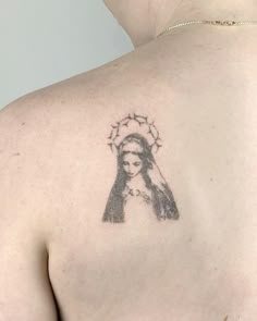 the back of a woman's shoulder with a tattoo of a virgin mary on it