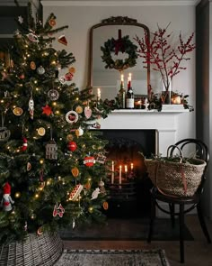 a decorated christmas tree in front of a fire place with candles and ornaments on it