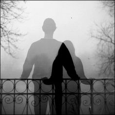 a man standing next to a fence in the fog