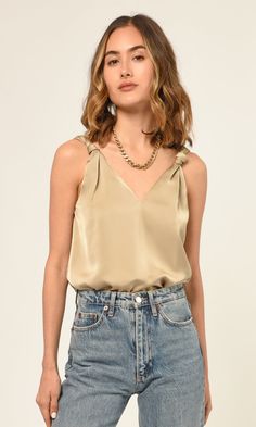 Designed from soft, luxurious satin, this beige V-neck top features knotted straps to give a flatteringly feminine look. Its understated elegance will have you shimmying into the night with confidence. Satin top V-neck Knotted straps Self: 100% Polyester Lining: 100% Polyester Length: 23 1/2" Chest: 18 1/2" Hand wash in cold water. Lay flat to dry. Low iron. Model is wearing a size small Style #: G236T6850 Shoulder Knots, Tops And Blouses, Luxury Women Fashion, Satin Top, Spring Trends, Feminine Look, Understated Elegance, Low Iron, V Neck Tops