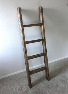 an old wooden ladder leaning against the wall in a room with carpeted flooring