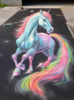 a chalk drawing of a unicorn with rainbow hair on the sidewalk in front of a garage