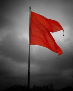 a red flag flying in the wind on a cloudy day with dark clouds behind it