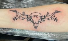 a bull's skull with barbed wire around it on the left side of the arm