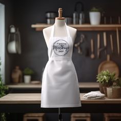 a white apron on a mannequin in front of a table with potted plants