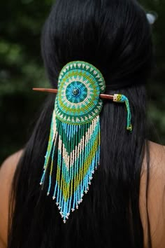 the back of a woman's head wearing a green and blue beaded hair piece