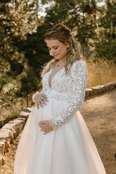 a pregnant woman wearing a white gown and holding her belly