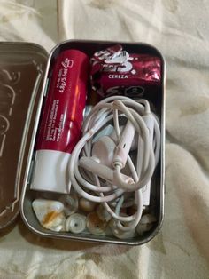 two tins filled with different types of items on top of a white bed sheet