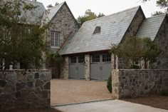 a stone house with two garages and an entry way leading to the front door