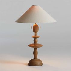 a wooden table lamp sitting on top of a white floor next to a light shade