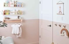 a baby's room with pink walls and wooden shelves on the wall next to a white chair