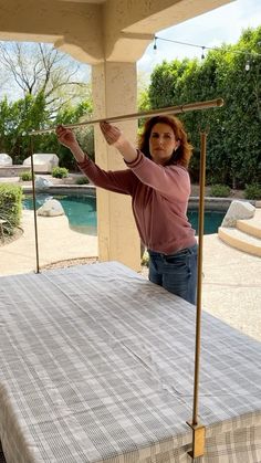 a woman standing on top of a bed in front of a pool and holding onto a pole