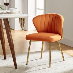 an orange chair sitting on top of a white rug next to a dining room table