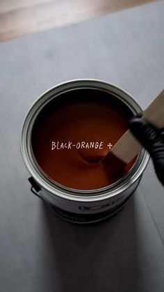 a paint can with the word black orange painted on it and a brush sticking out of it