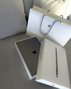 an apple laptop in a white box on a couch