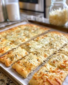 several slices of pizza sitting on top of a baking sheet in front of a glass jar