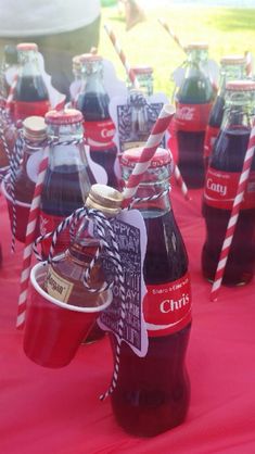 there are many soda bottles with straws in them on the red cloth tablecloth