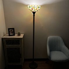 a lamp that is sitting on top of a floor next to a chair and table