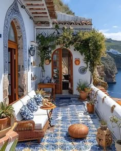 an outdoor patio with potted plants and seating area next to the ocean in front of it