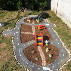 a toy car track made out of dirt and gravel in the middle of a yard