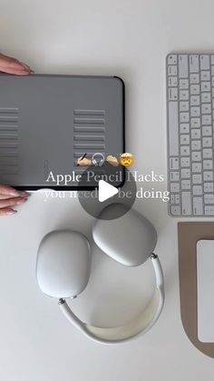 a person holding an apple device next to a keyboard and mouse on a white desk