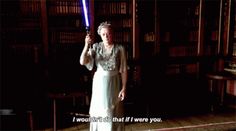 a woman holding a light saber in front of bookshelves with the words i wouldn't do that if i were you