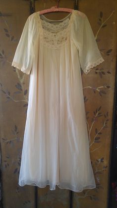 "60's lovely light beige nylon peignoir maxi nightie and sheer matching gown set. The nightie has beige lace shoulders and around front of the neck with brown eyelet embroidery across neck. The hem is lace also. The Gown is sheer double fabric. Same detail as nightie at front of the neck, it does up with two small buttons at the front of neck. mid length wide sleeves with lace at ends. Nightie : arm to arm across 18\" (36 bust) length 52\" **A few teeny tags in outer gown**" 1960s Lingerie, Night Gowns, Peignoir Sets, Eyelet Embroidery, Women's Nightgowns, Nightgowns, Wide Sleeves, Sheer Sleeves, Lingerie Collection