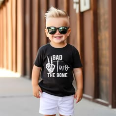 a young boy wearing sunglasses and a black t - shirt that says bad two the bone