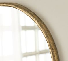 an oval mirror hanging on the wall next to a window