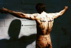 a man standing in front of a brick wall with his back turned to the camera