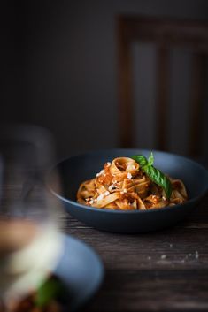 a blue bowl filled with pasta on top of a wooden table