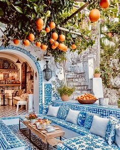 an outdoor living area with blue and white tiles on the walls, oranges hanging from trees