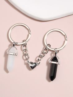 two key chains with charms attached to them on a pink surface, one has a heart and the other has a crystal point