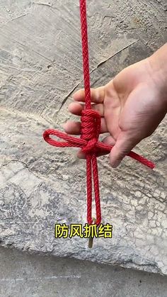 a hand holding a red rope on top of a stone slab with writing in chinese