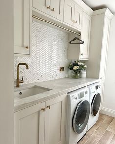 a washer and dryer in a white kitchen with herringbone backsplash