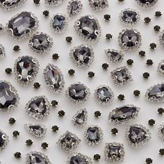 an assortment of black and white diamonds on a white surface with lots of smaller ones in the background