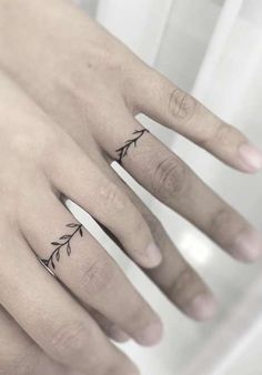 two fingers with tattoos on them, one has an arrow and the other has a red dot