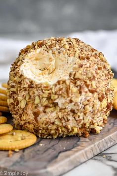 a cheese ball is on a wooden board surrounded by crackers