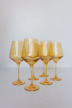 five yellow wine glasses lined up on a white surface